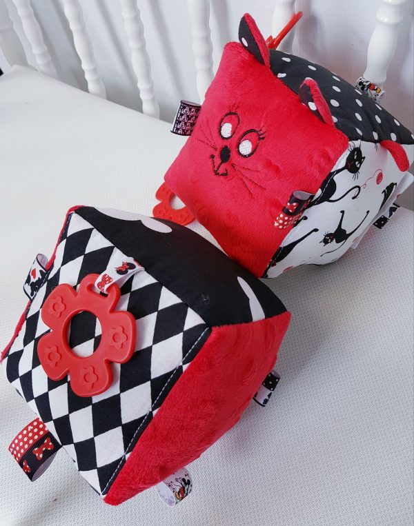 Duża kontrastowa kostka sensoryczna uszyta z bawełny w kontrastowych kolorach czarno - biało - czerwonych. Na jednym z boków haft buźki kotka i uszka. 